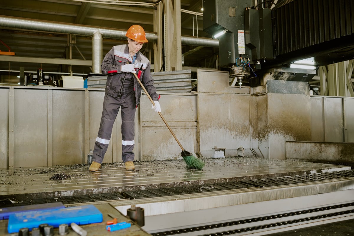 Schoonmaakmedewerker bezig in een industriële werkplaats