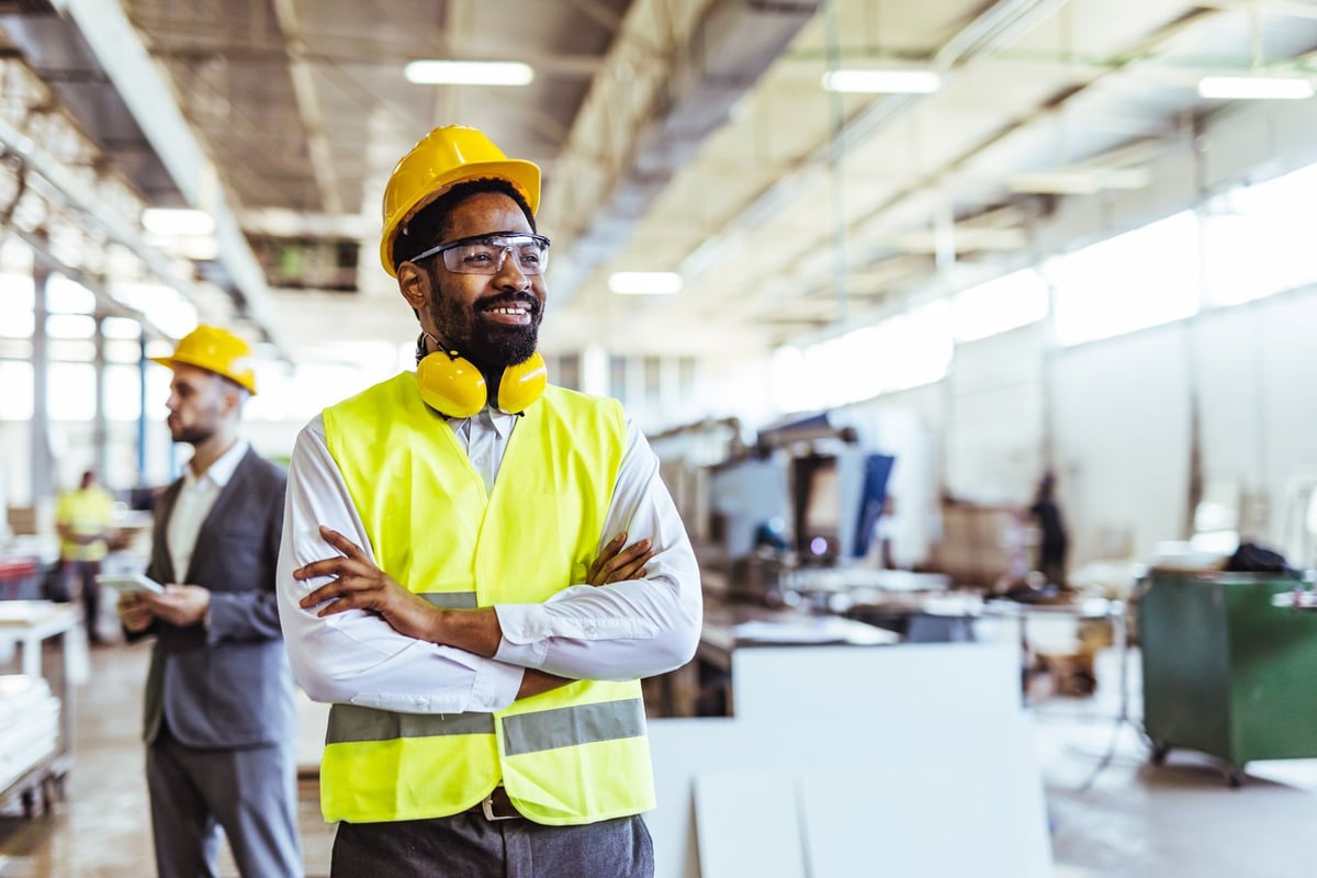 Lachende productiemedewerker met beschermingsuitrusting in een fabriek
