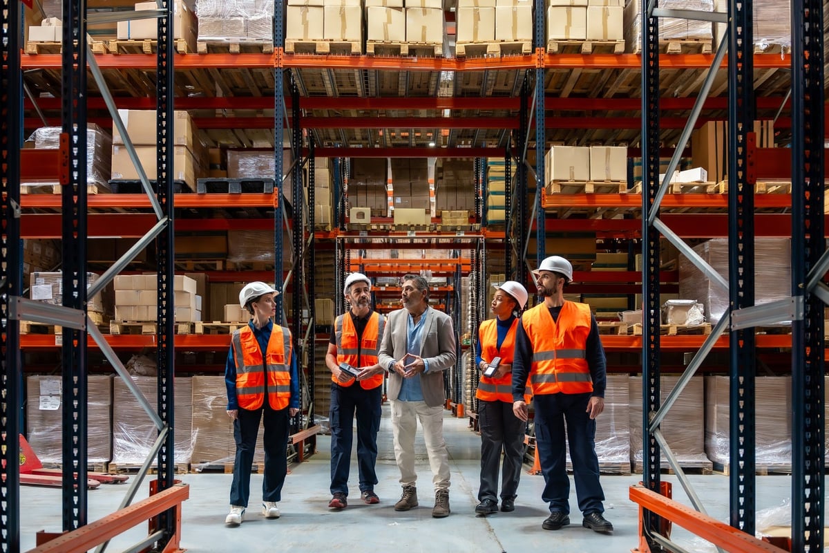 Manager en magazijnmedewerkers bespreken logistiek in een groot industrieel pakhuis