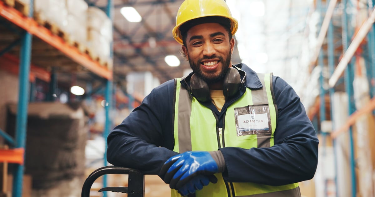 Lachende magazijnmedewerker met trolley in een logistiek depot