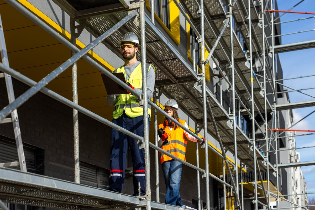 Twee ingenieurs in veiligheidskleding op een bouwsteiger